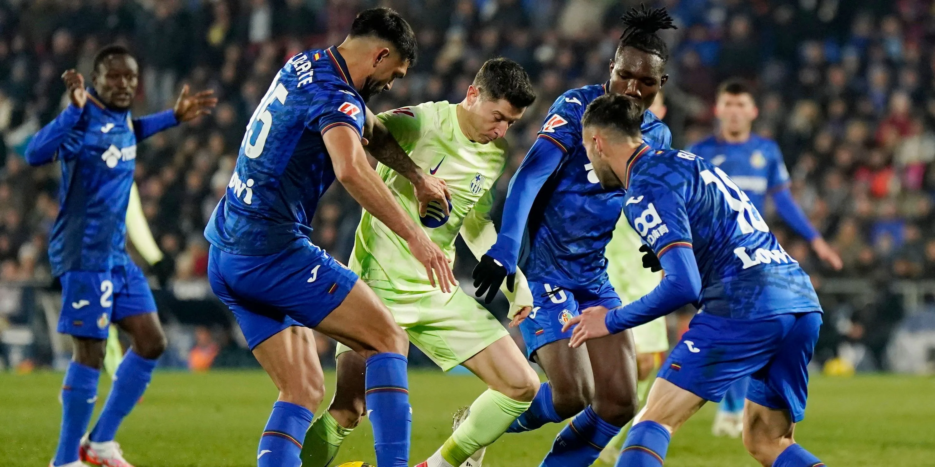 Tiền vệ Christantus Uche của Getafe trong pha tranh chấp bóng với Robert Lewandowski của Barcelona